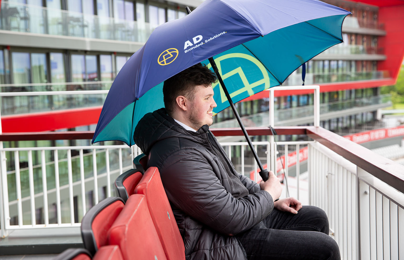 a man sitting on a bench holding an umbrella.