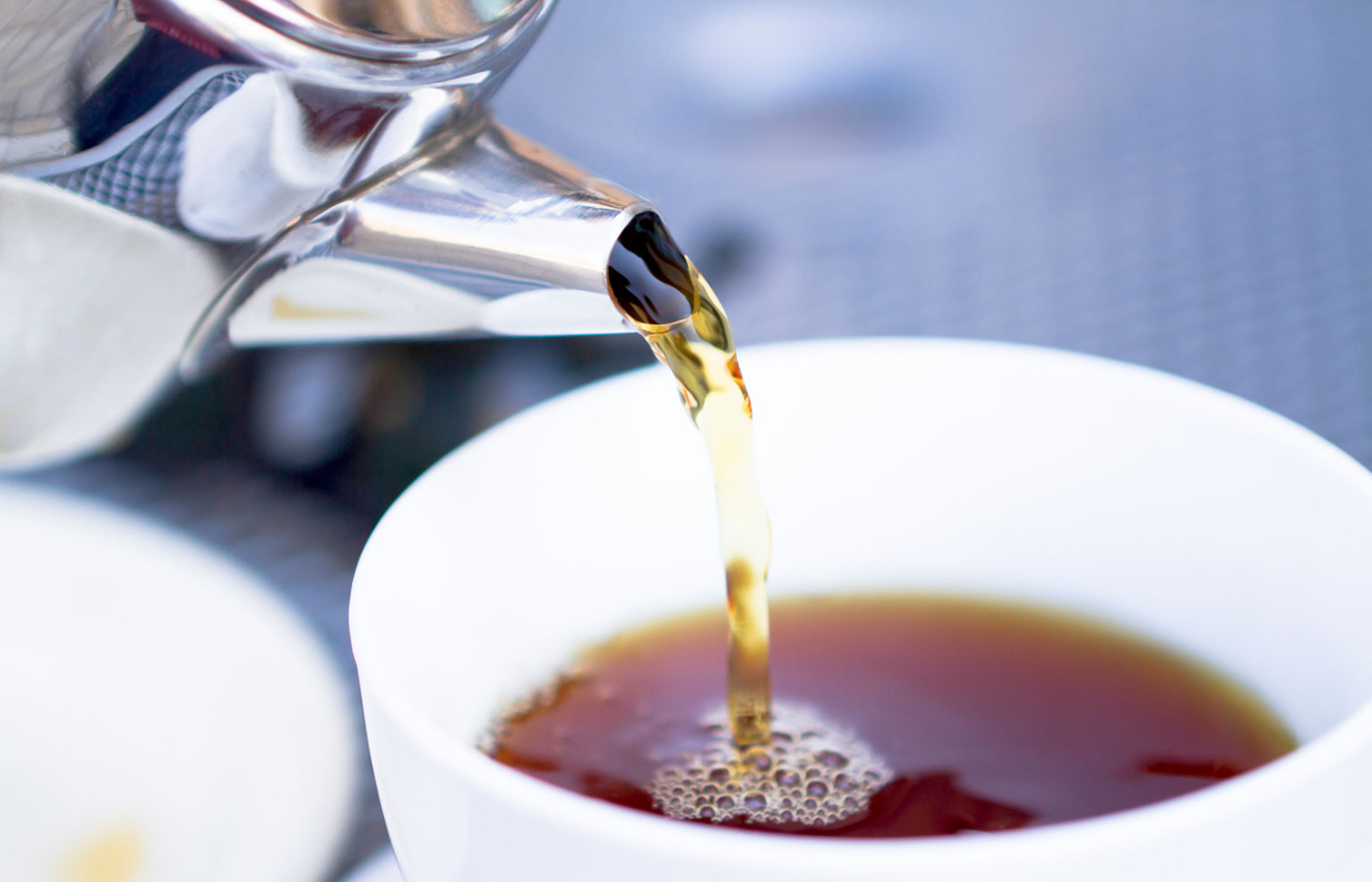 Pouring a kettle of hot water into a cup of tea