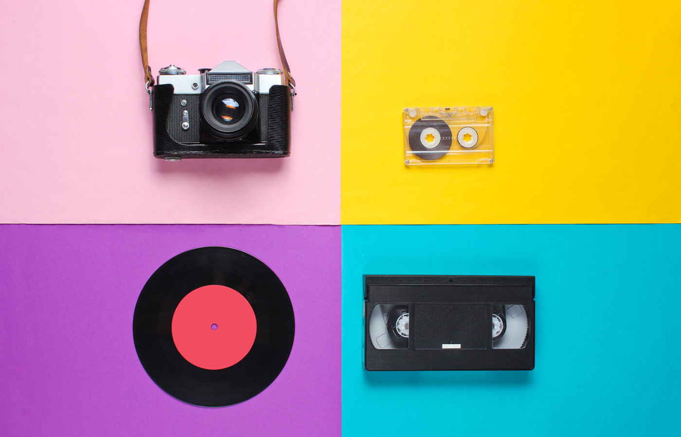 A colourful image featuring a camera, a tape, a vinyl record and a video tape