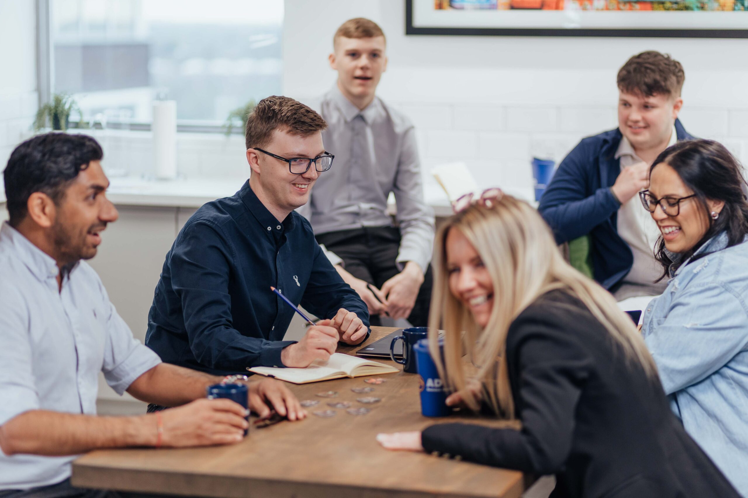 a group of people sitting around a wooden table.