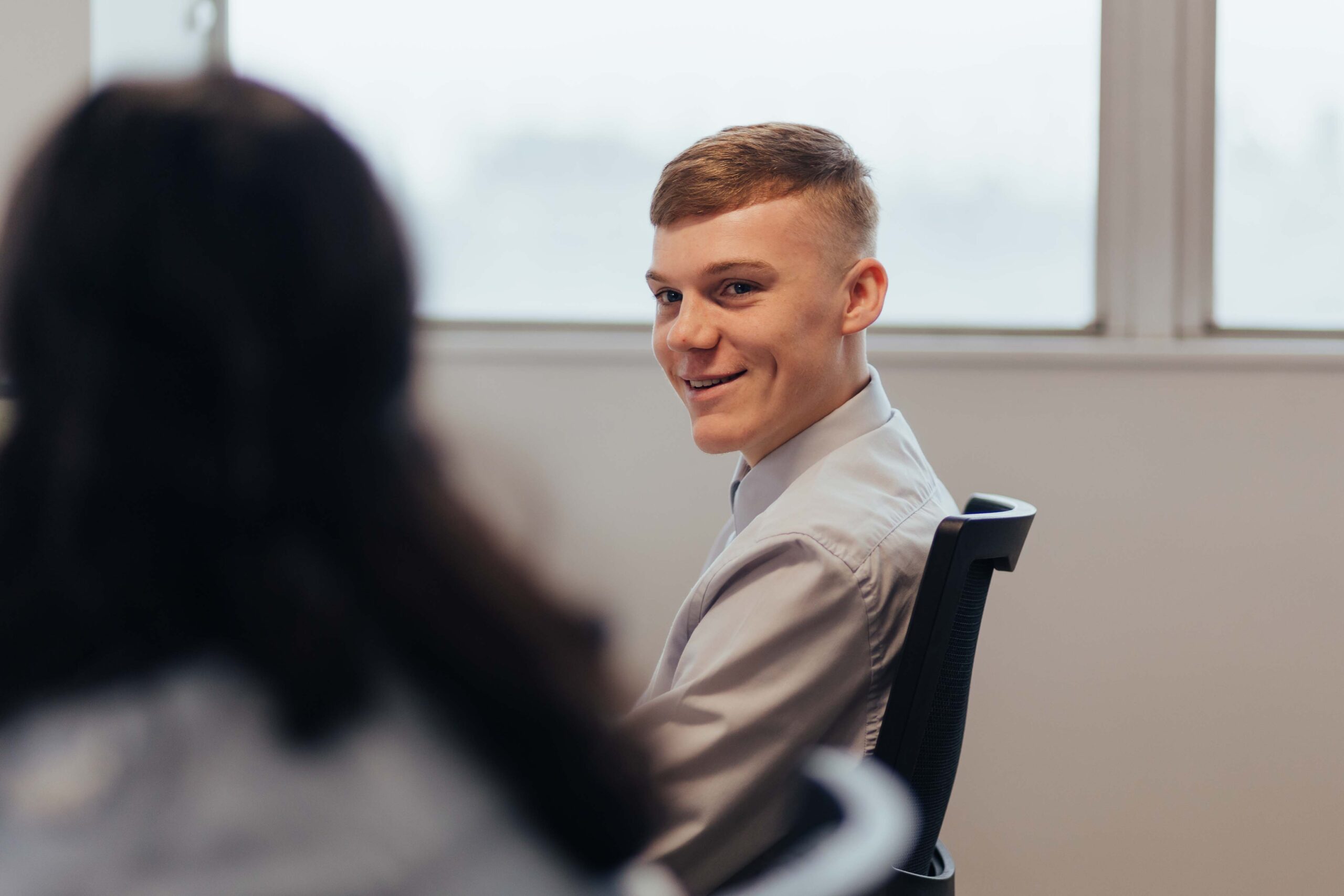 a man sitting in a chair smiling at a woman.