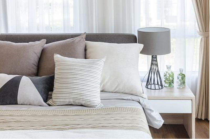 a bed with pillows and a lamp on a table.