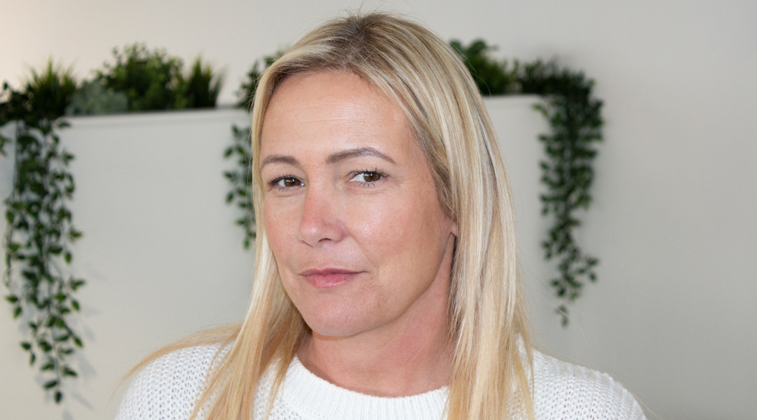 a woman with long blonde hair and a white sweater.