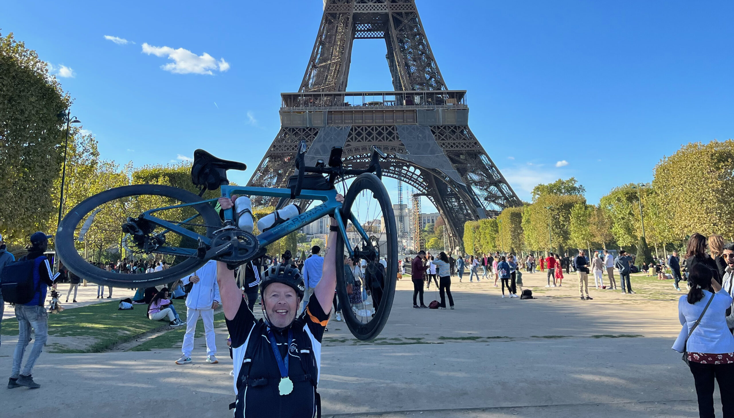 Peter lifting up his bike in celebration in front of the Eiffel tower